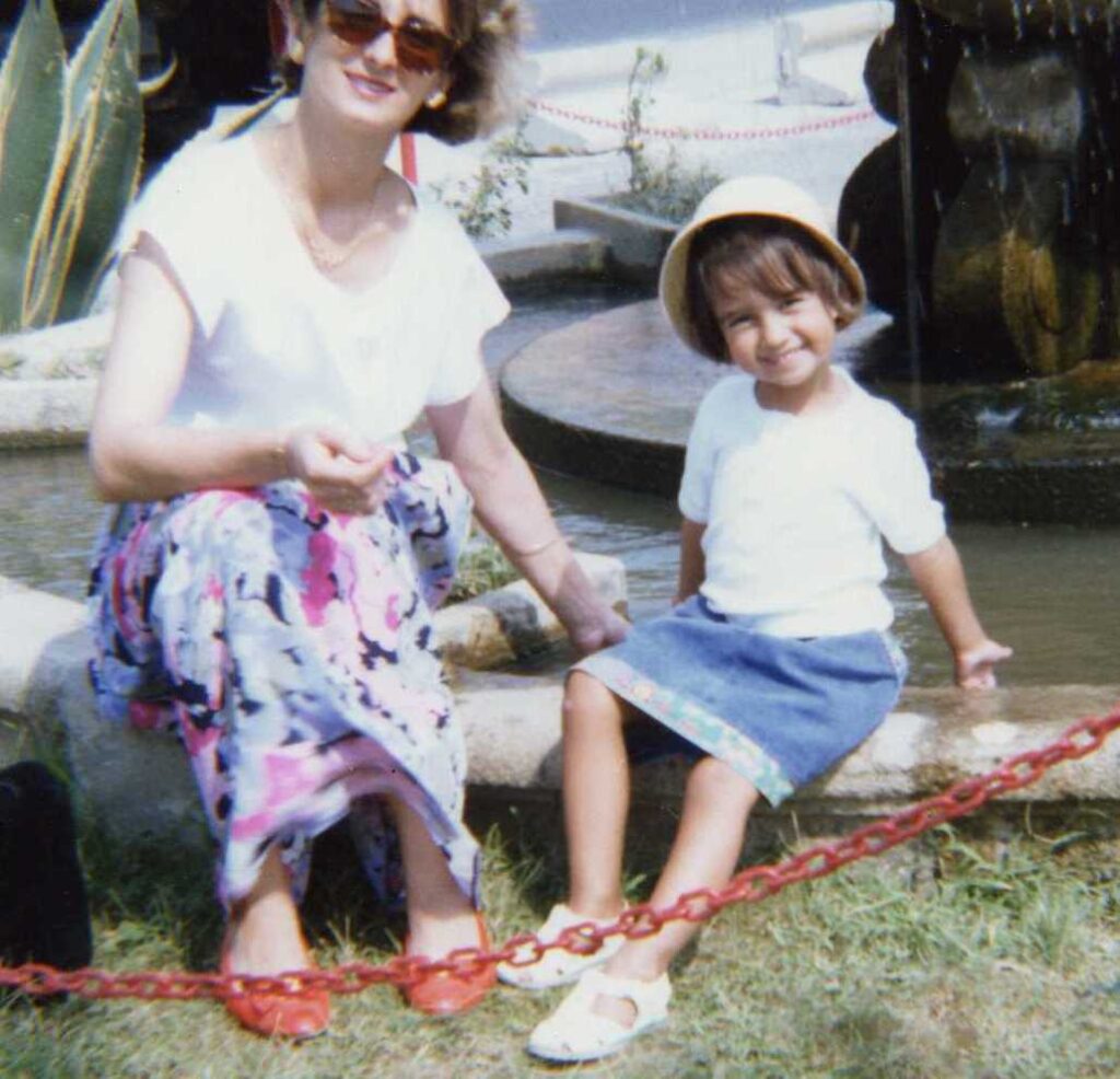 Andreia is about 4 years old and is sitting by a fountain next to her mom