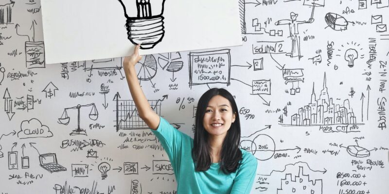 woman draw a light bulb in white board